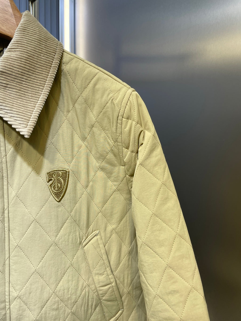 Yellow quilted jacket with Burberry crest patch and diamond stitching.