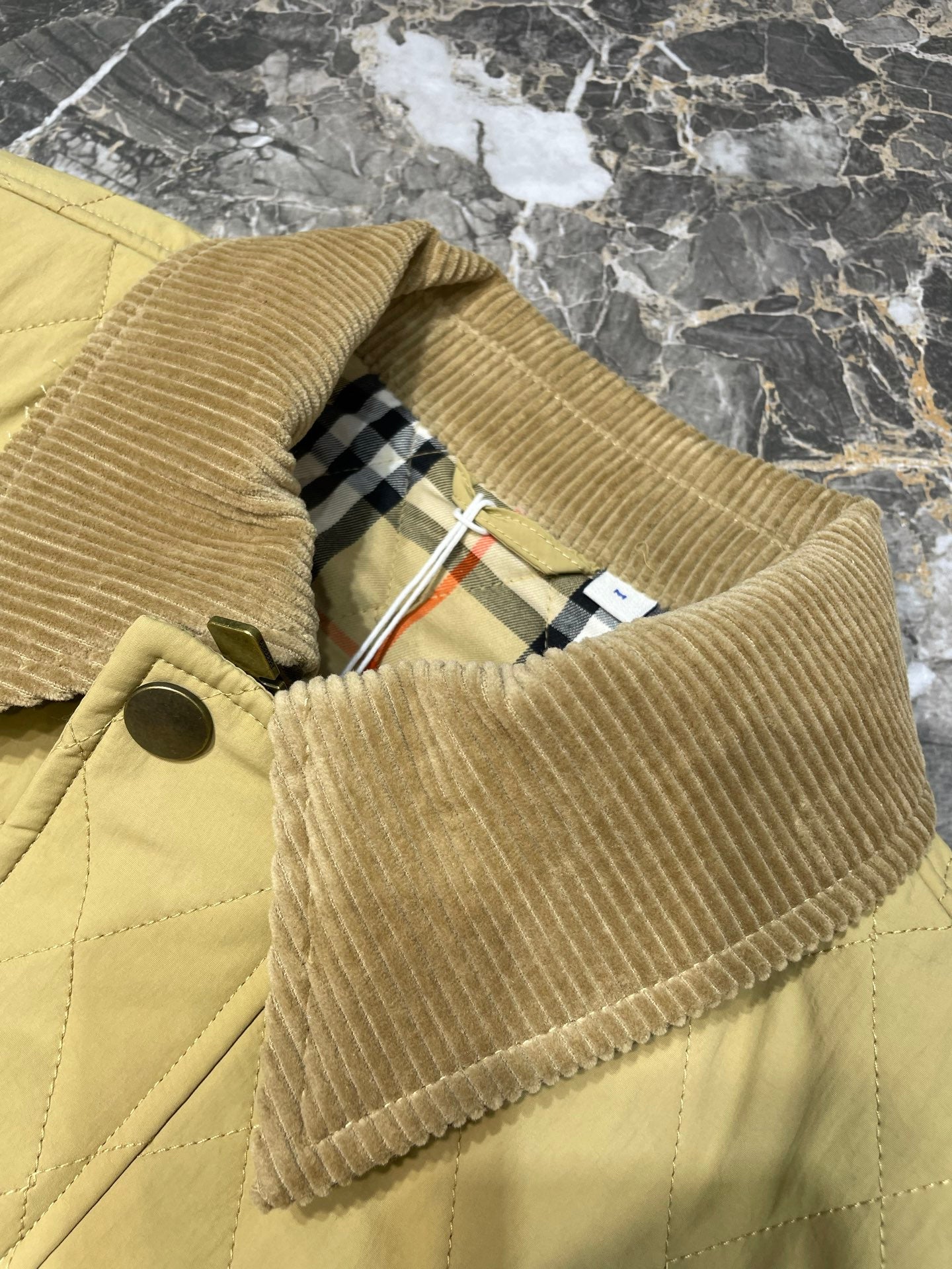 Long quilted coat with corduroy-like collar and plaid lining, button detail