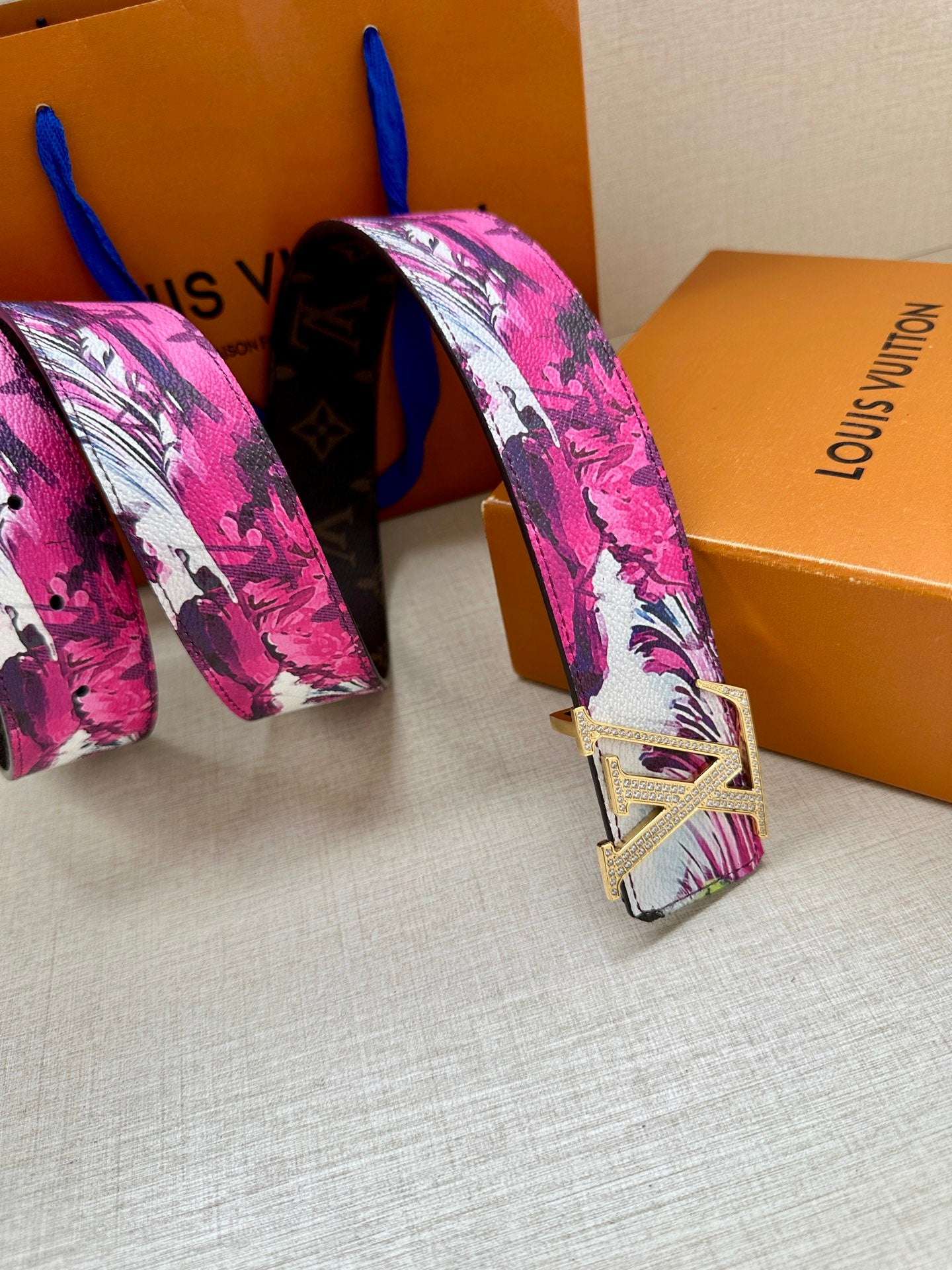 Louis Vuitton belt with pink floral strap and silver LV buckle, folded end view.