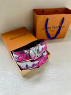 Louis Vuitton belt with pink floral canvas strap and silver LV buckle, laid flat.
