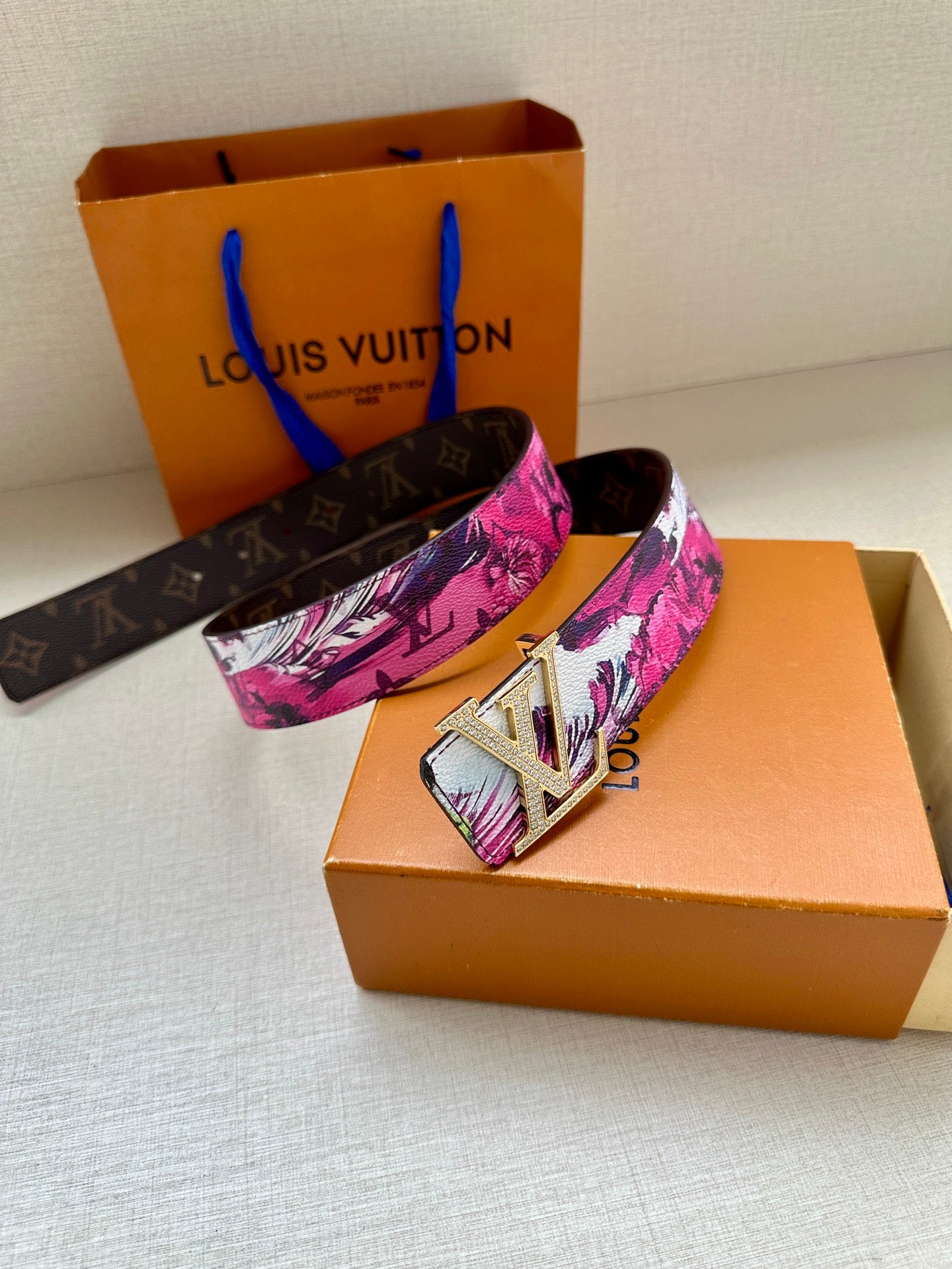 Louis Vuitton belt with pink floral canvas strap and silver LV buckle, side view.