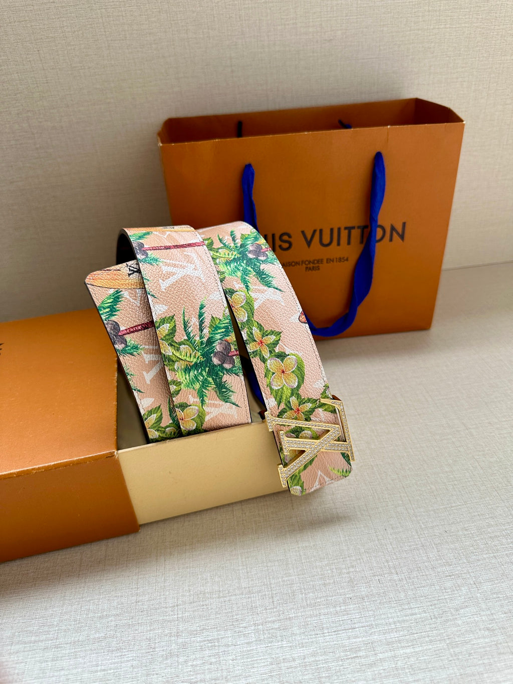 Louis Vuitton belt in profile: pink floral strap with silver LV buckle and green floral motifs