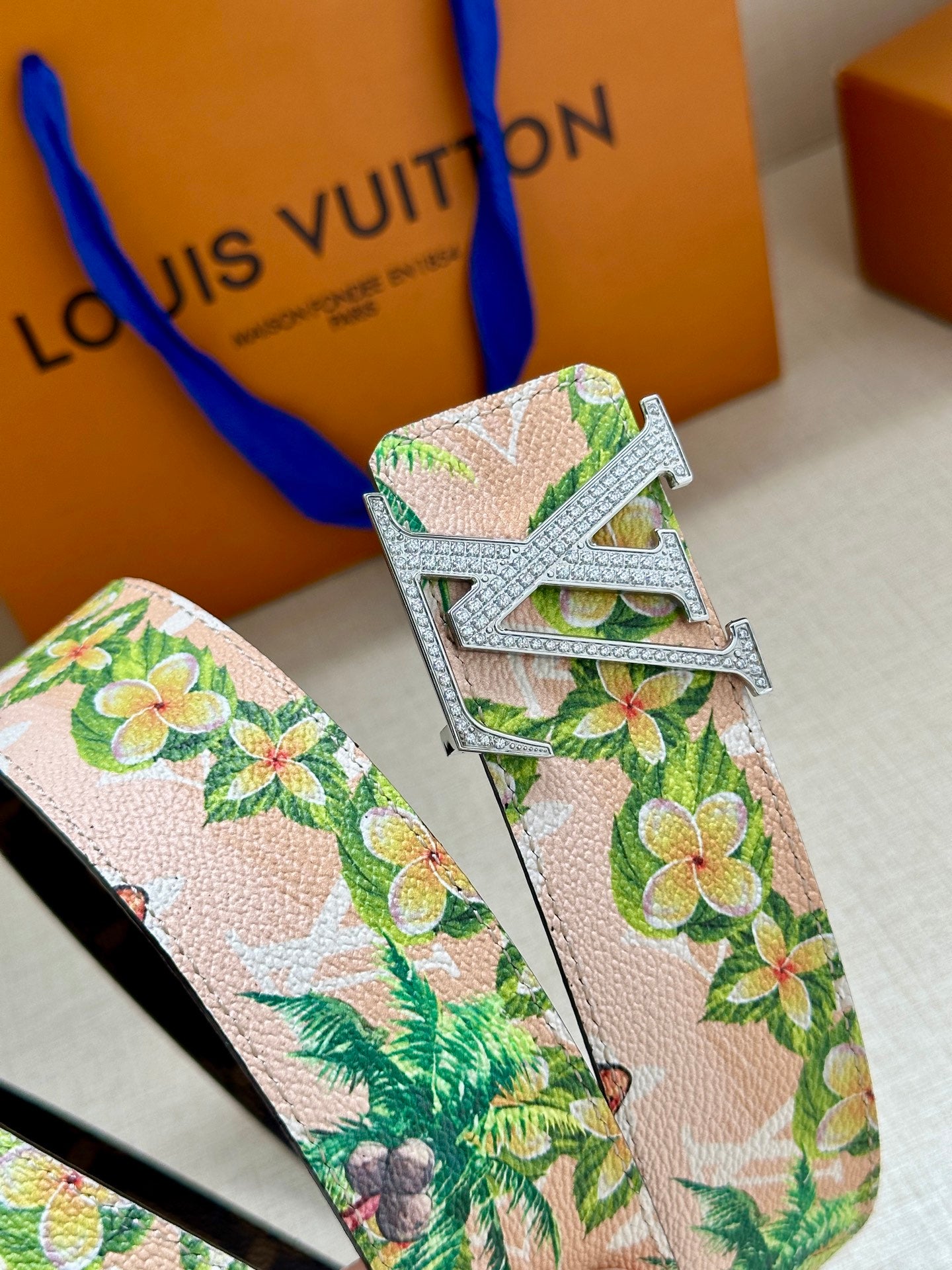Louis Vuitton belt buckle detail on pink floral strap with green leaves and flowers