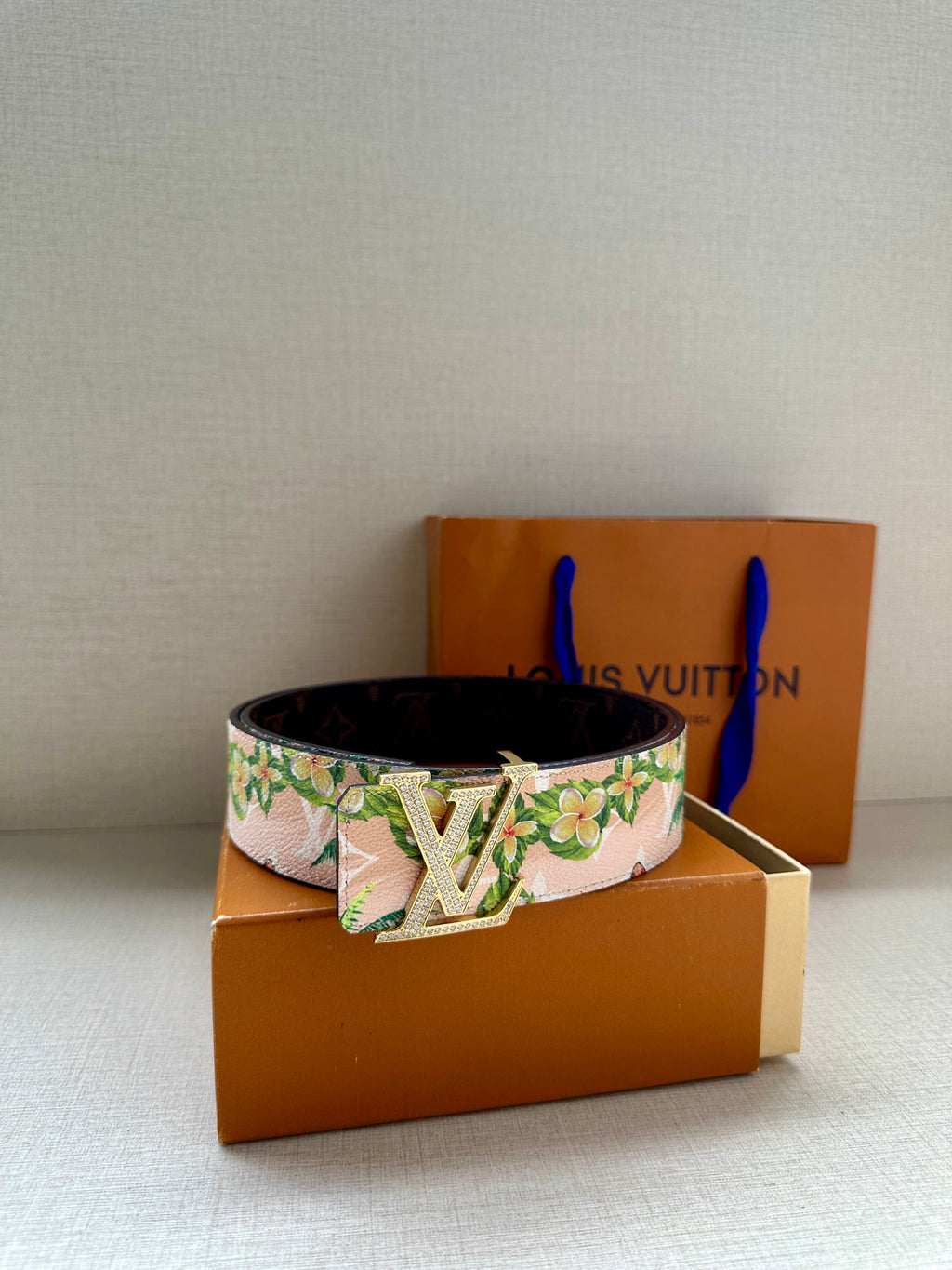 Louis Vuitton belt with pink floral strap and silver LV buckle, dark underside visible