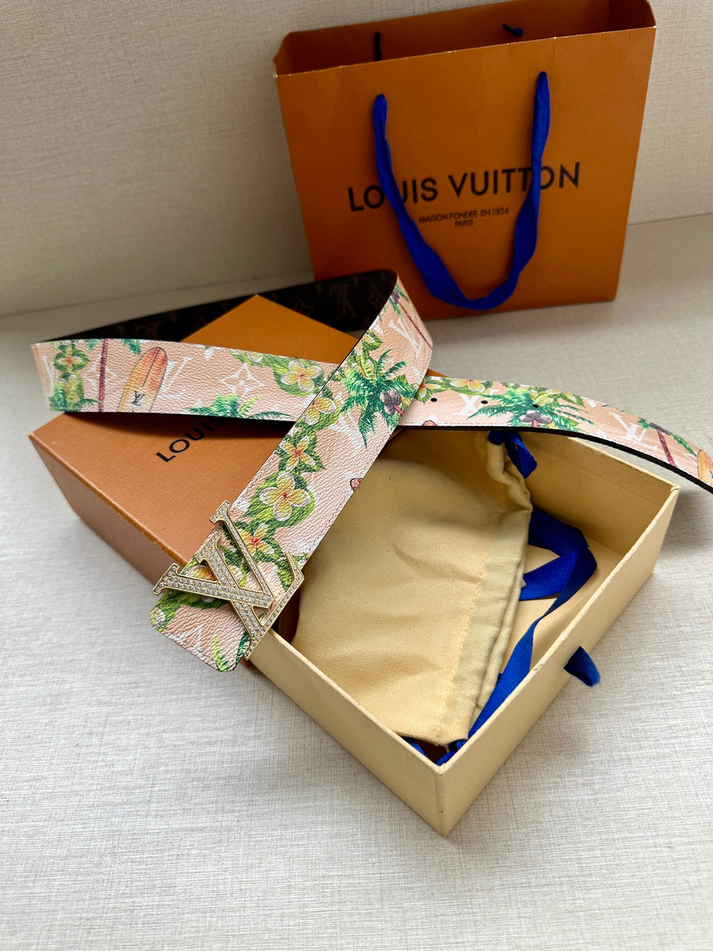 Louis Vuitton belt laid open: pink floral strap with silver LV buckle on dark underside