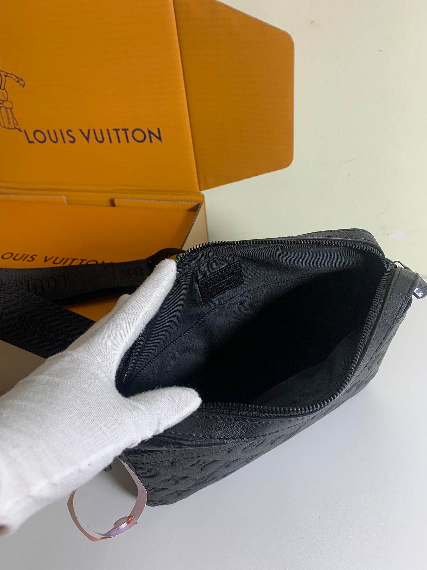 Louis Vuitton crossbody bag with dark fabric lining and open zipper at the top.