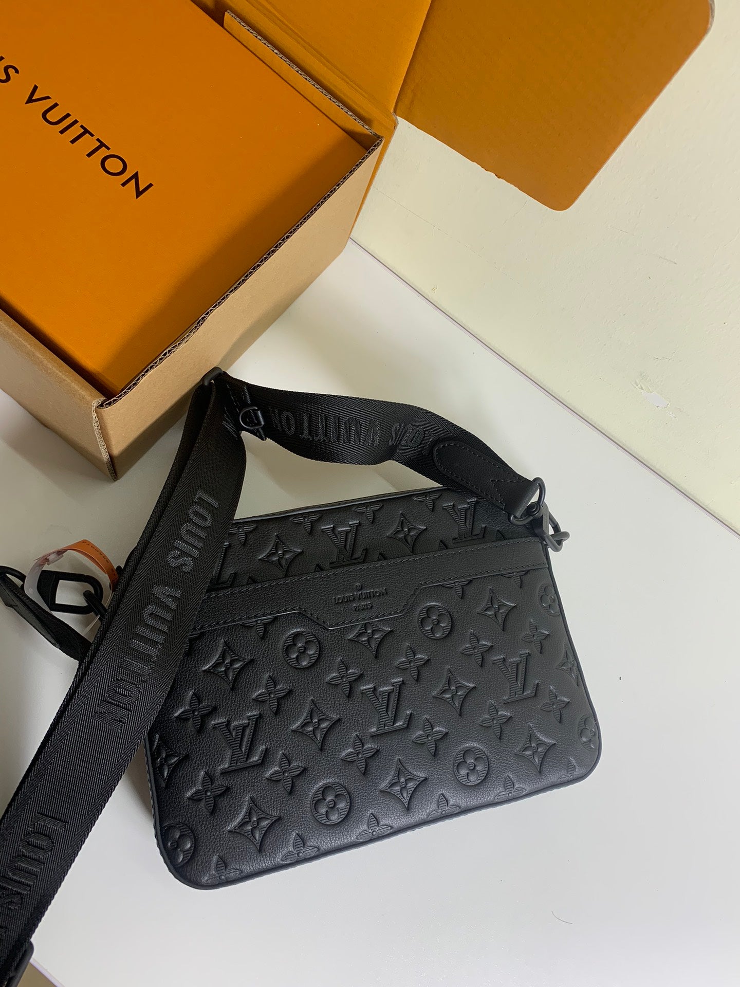 Louis Vuitton crossbody bag in dark monogram leather with adjustable strap and zipper top.