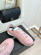 Pink Chanel low-top sneakers, angled view on black display box