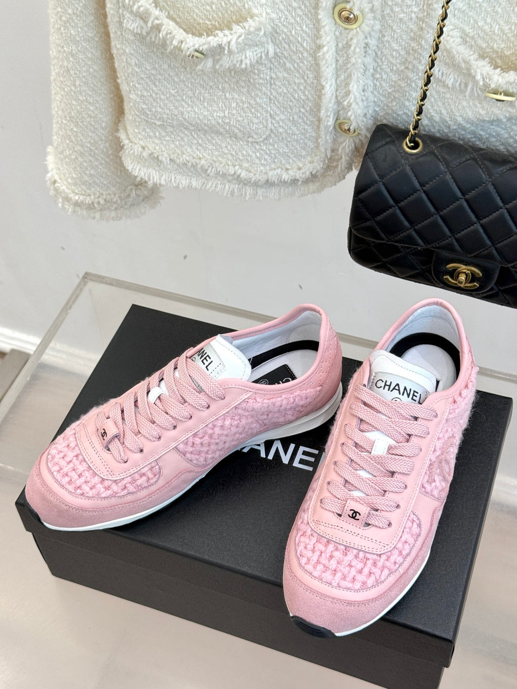 Pink Chanel low-top sneakers, pair shown front and side on black box