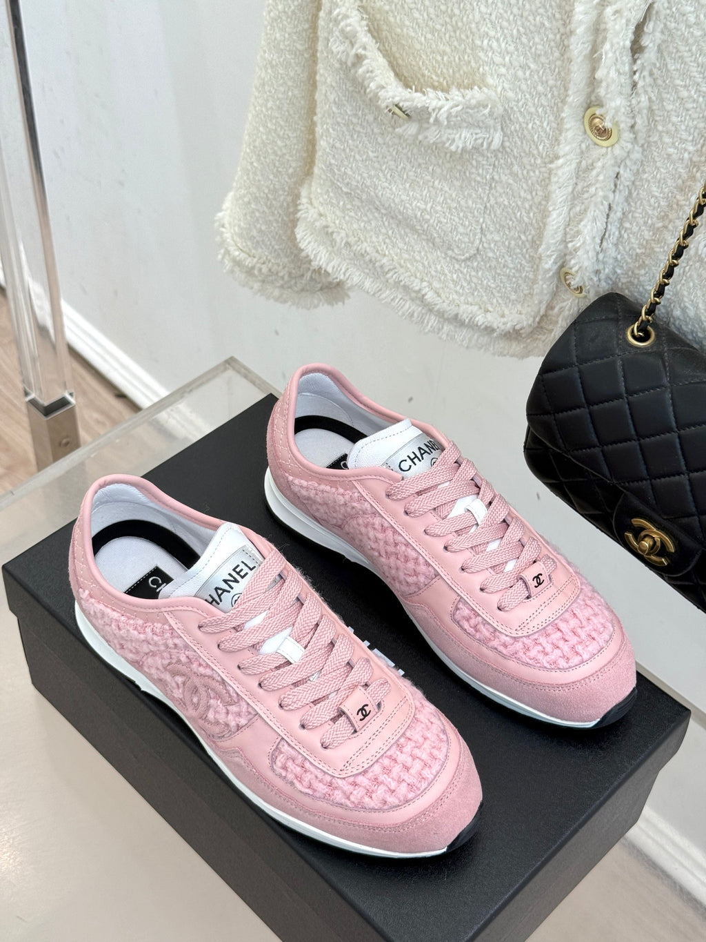 Pink Chanel low-top sneakers, side-by-side on black display box