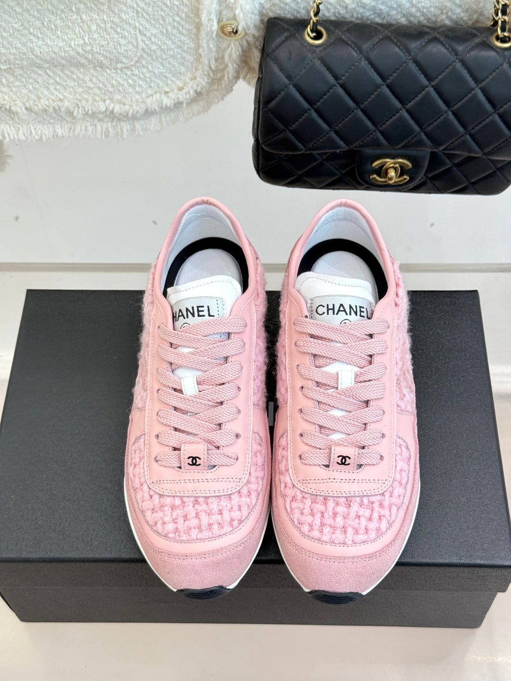 Pink Chanel low-top sneakers with front logo and lace-up closure on black box