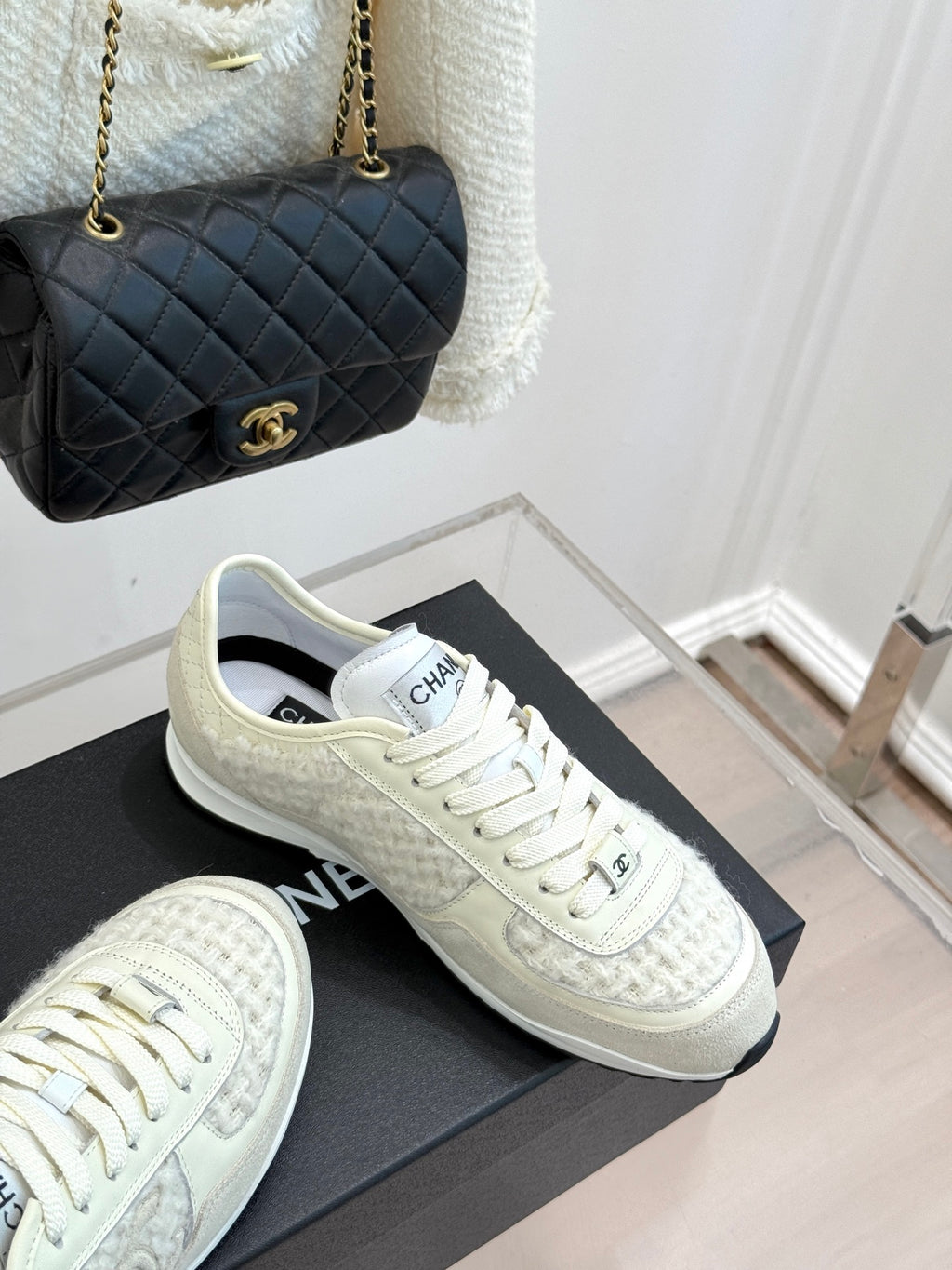 White Chanel sneakers on black box, textured uppers and lace-up closure