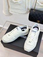 White Chanel sneakers pair with lace-up vamps and CHANEL tongue label on box