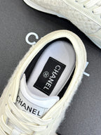 White Chanel sneakers close-up, CHANEL logo patch on tongue