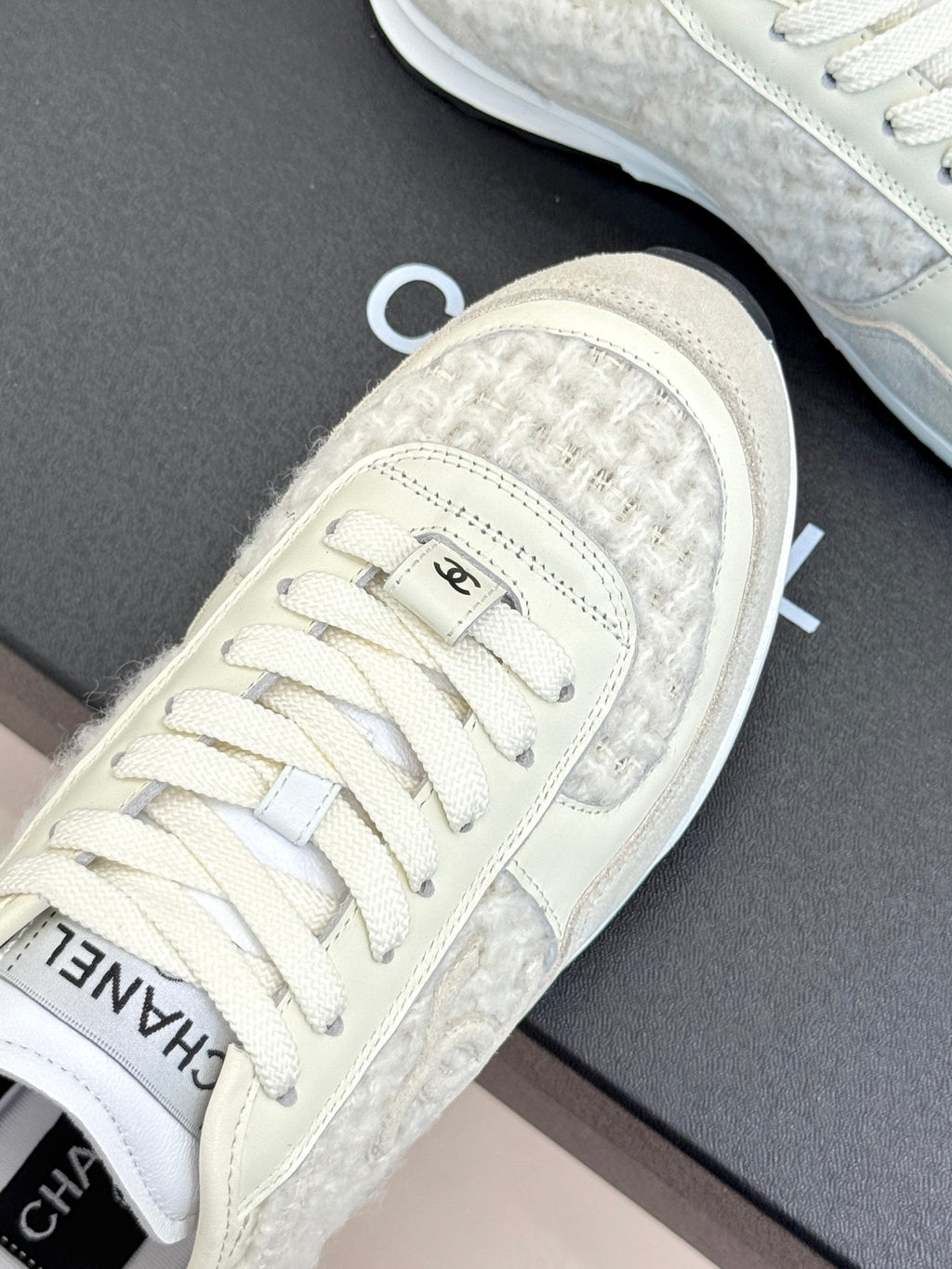 White Chanel sneakers close-up, CHANEL logo on laces and textured toe