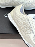 White Chanel low-top sneaker close-up, embossed CC on textured side panel