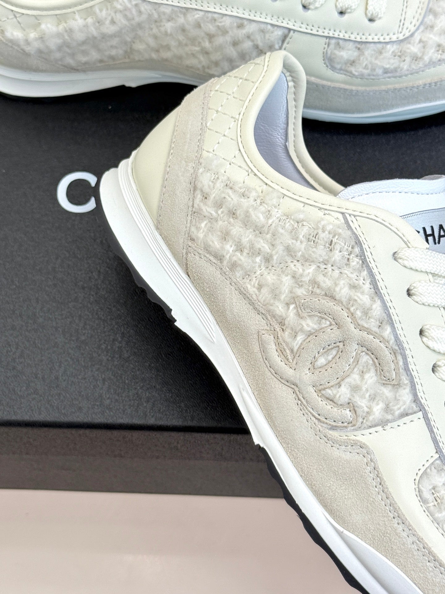 White Chanel low-top sneaker close-up, embossed CC on textured side panel