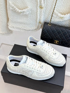 White Chanel sneakers side view, lace-up with logo detailing on textured uppers