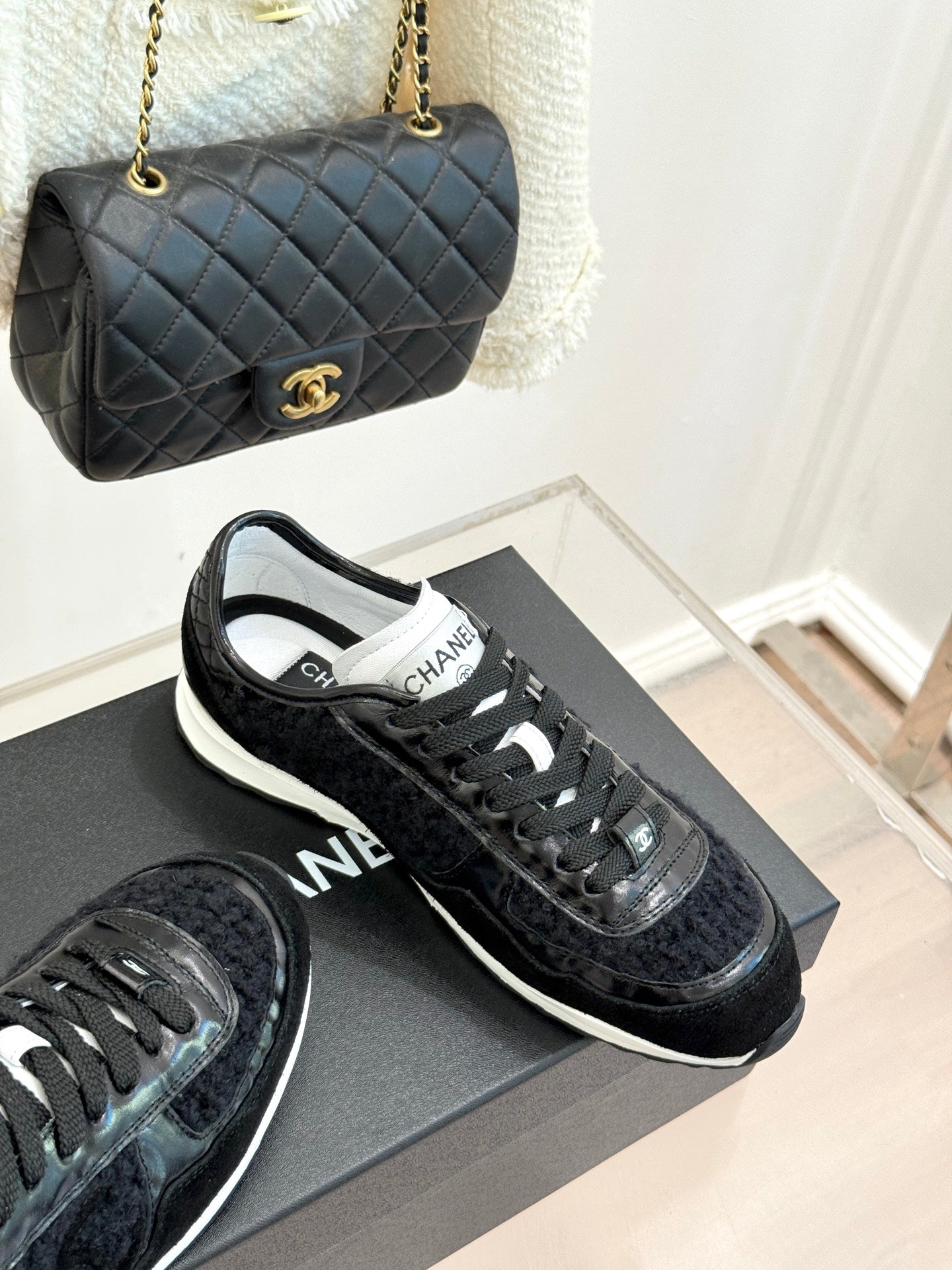 Chanel black lace-up sneakers with textured uppers on display with matching bag