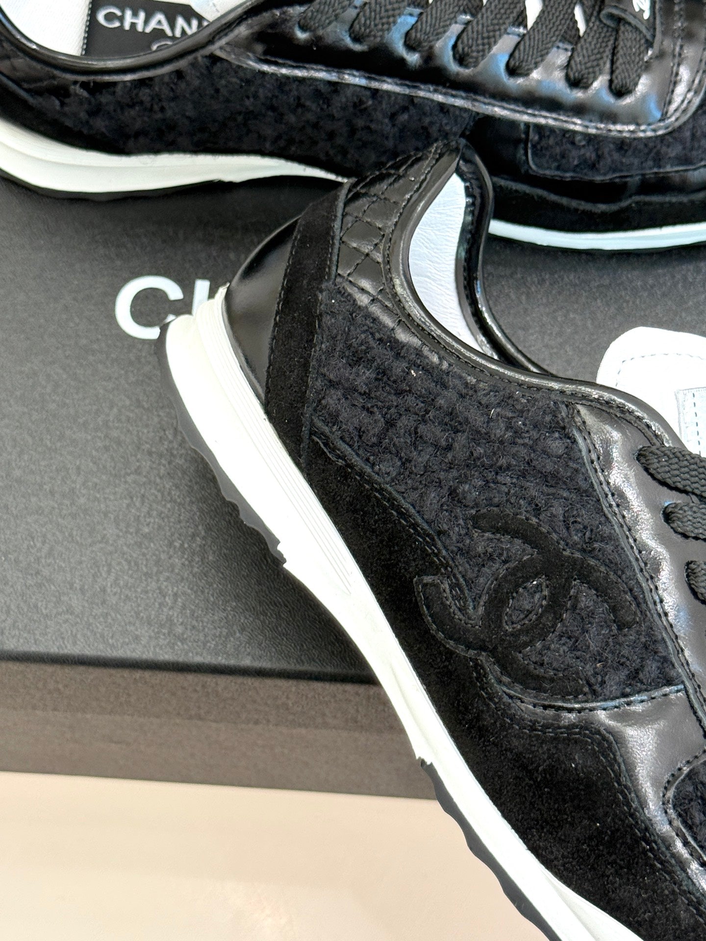 Chanel sneaker close-up: black textured panels with white midsole and laces