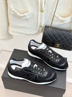 Pair of Chanel black sneakers with white trim, side-by-side on shoe boxes