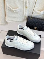 White Chanel sneakers with lace-up design and logo detailing