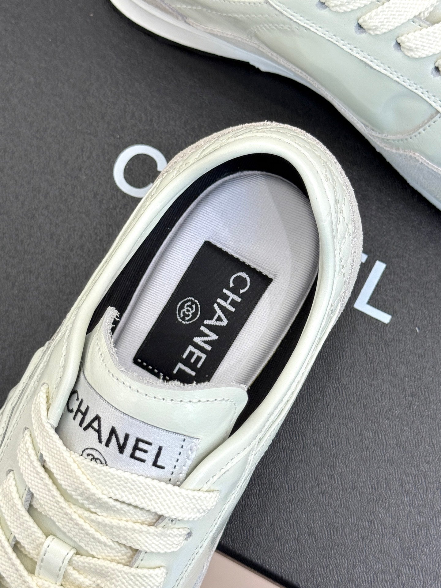 White Chanel sneaker close-up, branded tongue tag and lace-up