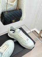 White Chanel sneakers with lace-up design beside black quilted handbag