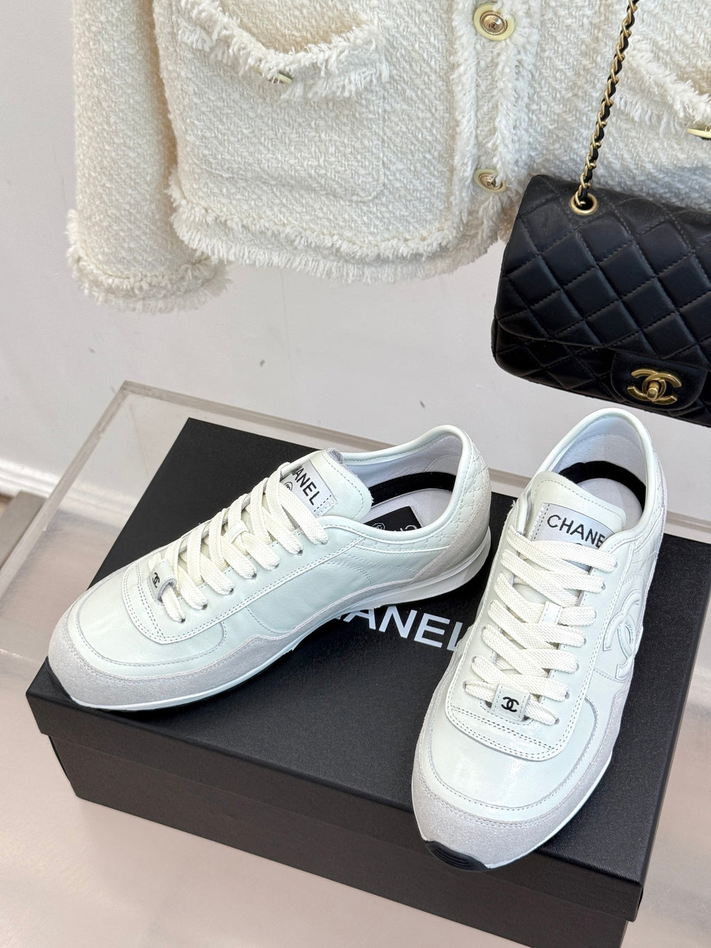 Pair of white Chanel sneakers on black shoebox, front view