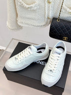 Pair of white Chanel sneakers on black shoebox, front view