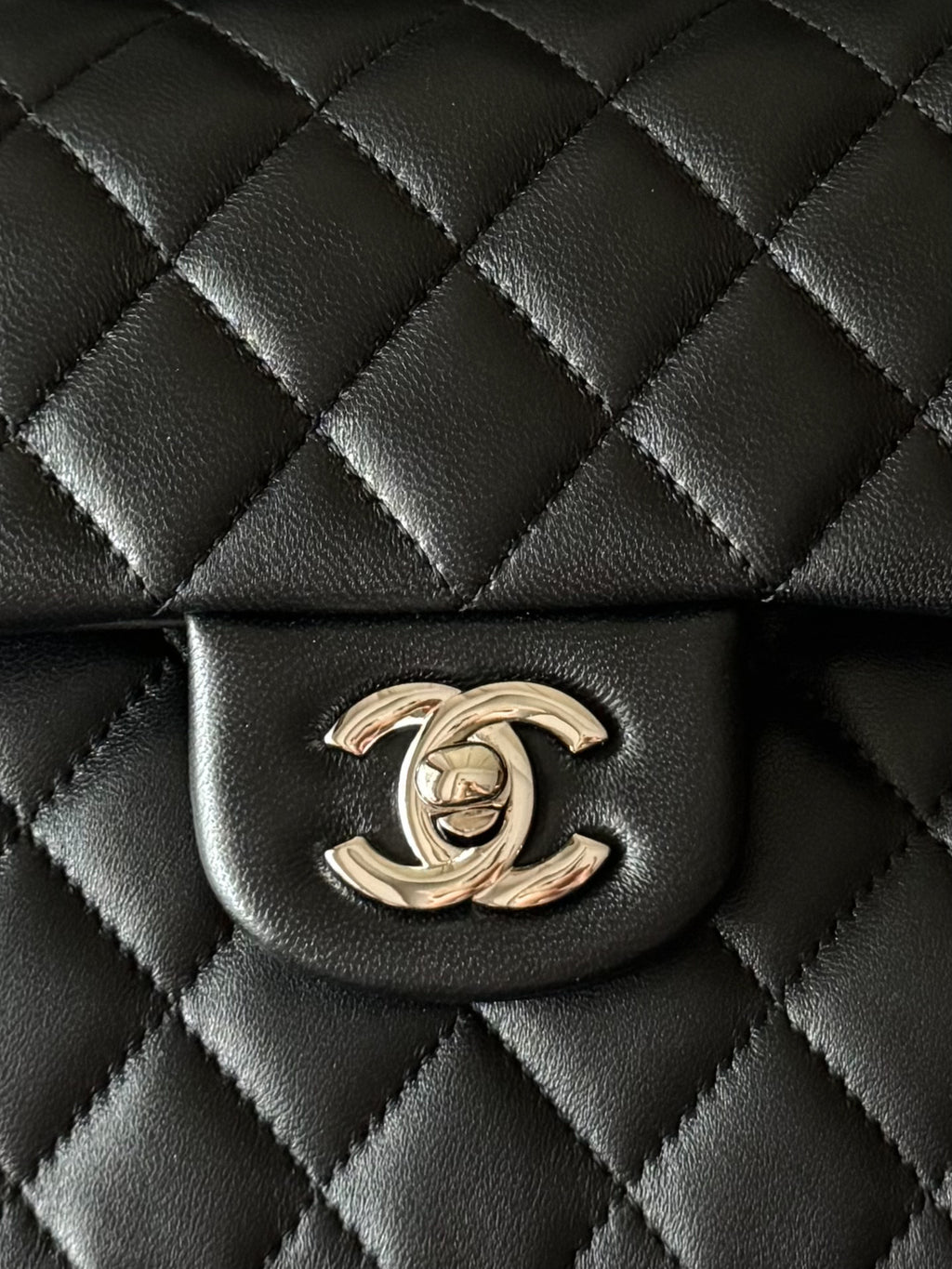 Black quilted bag front with gold CC emblem under the flap.
