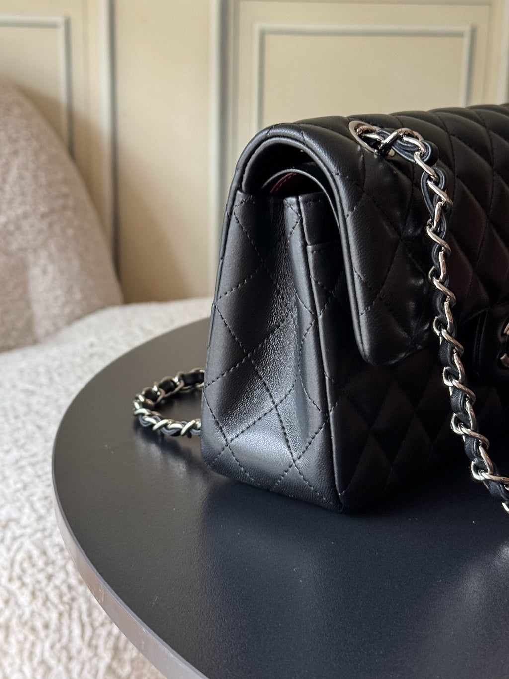 Black quilted Chanel bag corner with rolled flap and silver chain shoulder strap.