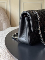 Black quilted Chanel bag corner with rolled flap and silver chain shoulder strap.
