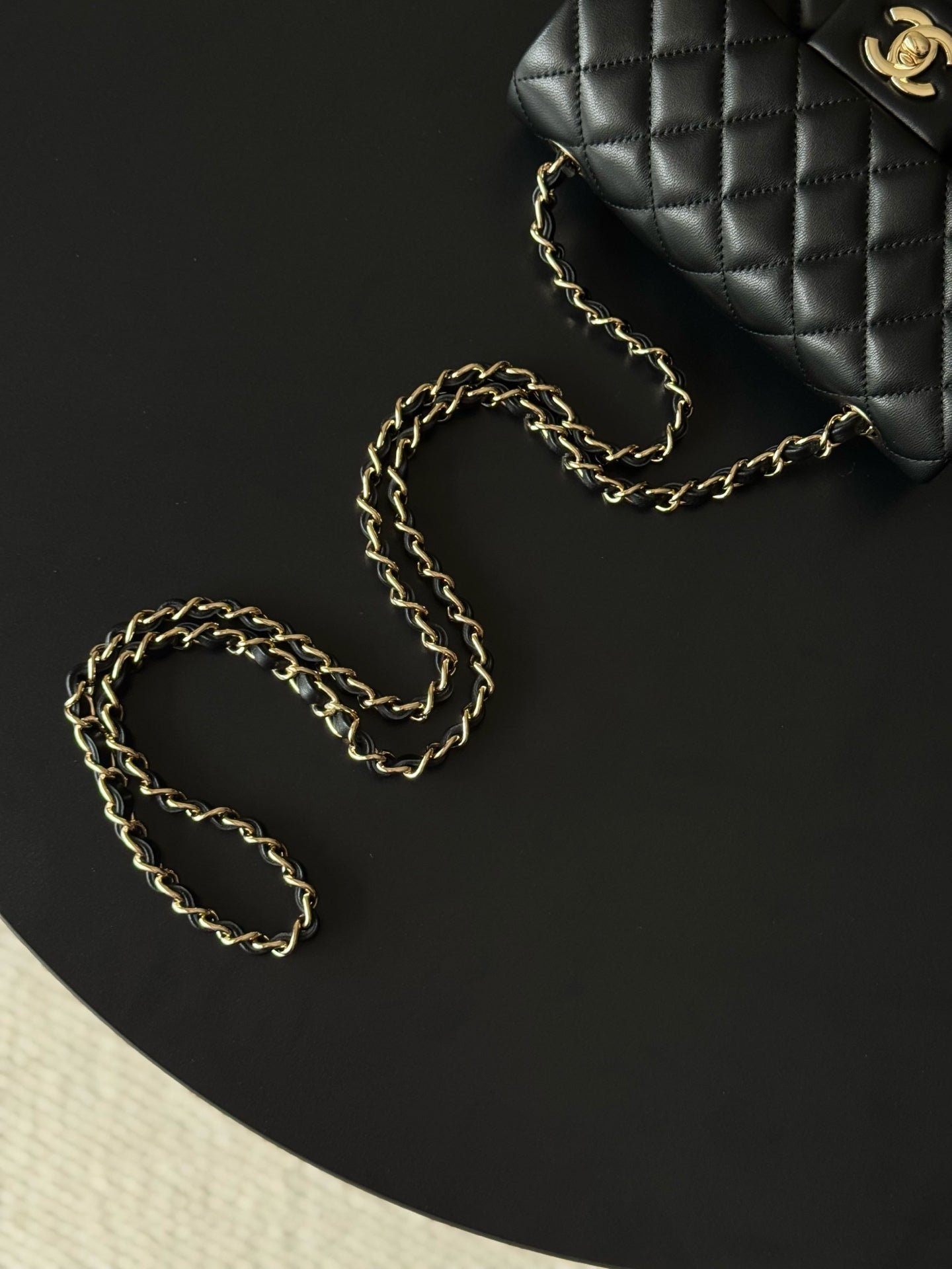 Chanel quilted shoulder bag with gold chain lying beside it