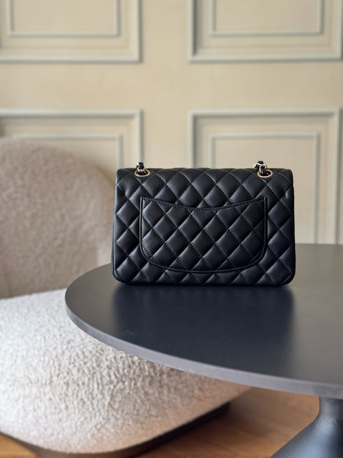 Black quilted Chanel flap bag with small top handle and gold-tone chain detail