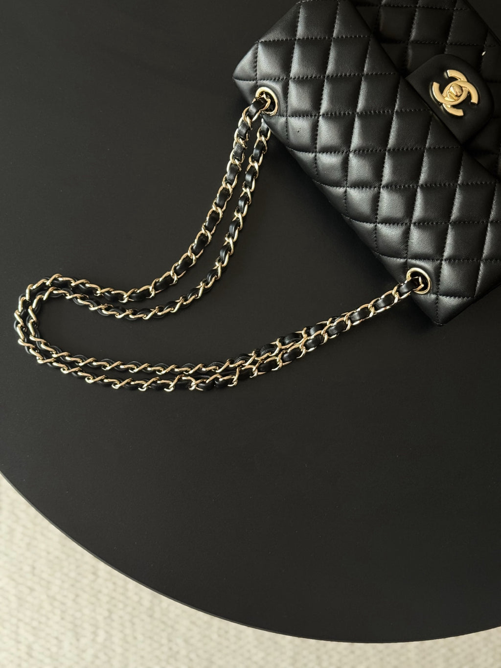 Black quilted Chanel bag with gold-tone chain strap on display surface