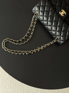 Black quilted Chanel bag with gold-tone chain strap on display surface