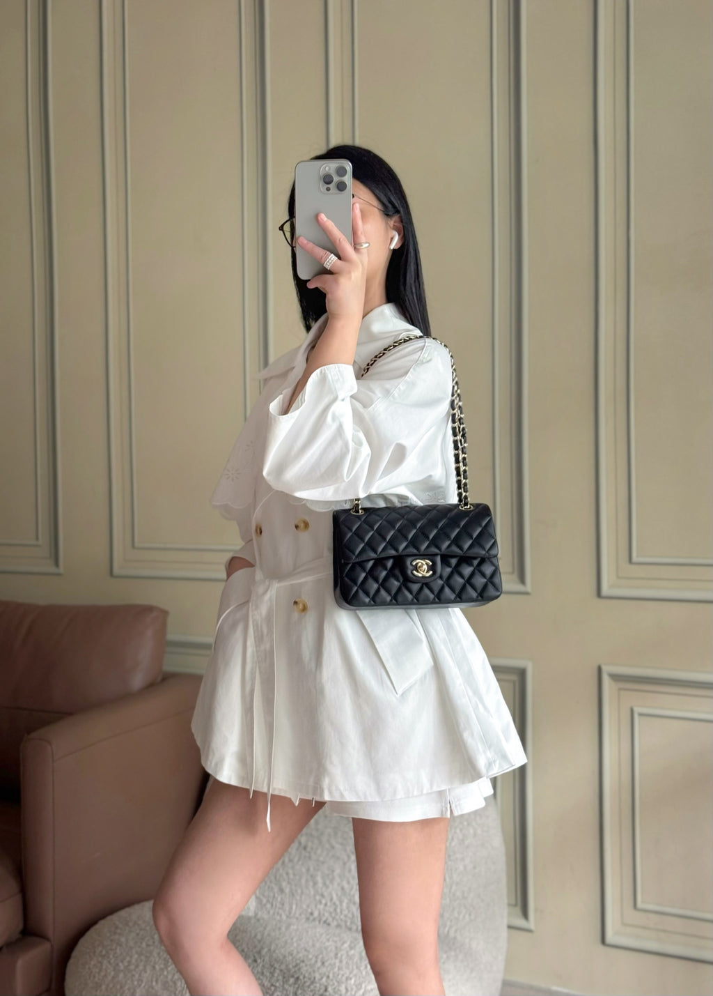 Small black quilted Chanel crossbody flap bag worn with a white dress