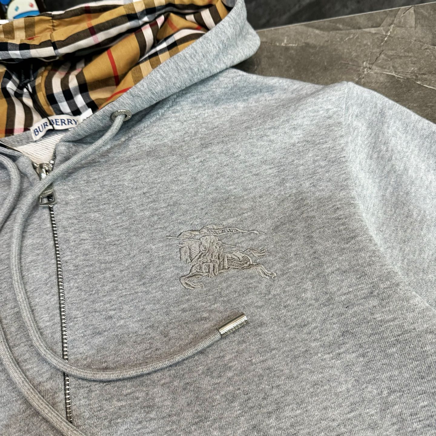 Light gray zip-up hoodie close-up with Burberry horse logo and zipper