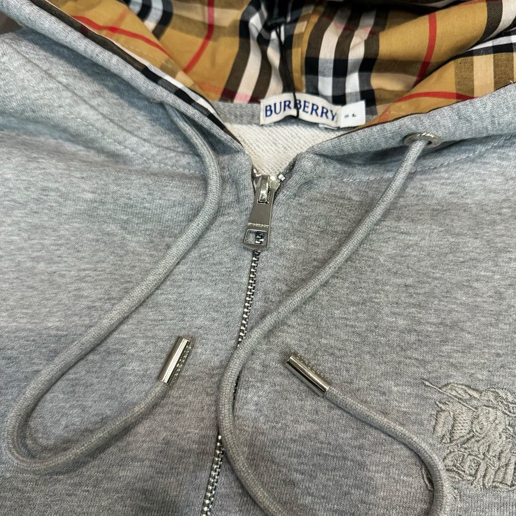 Light gray hoodie close-up: zip placket, metal zipper pull, drawstrings
