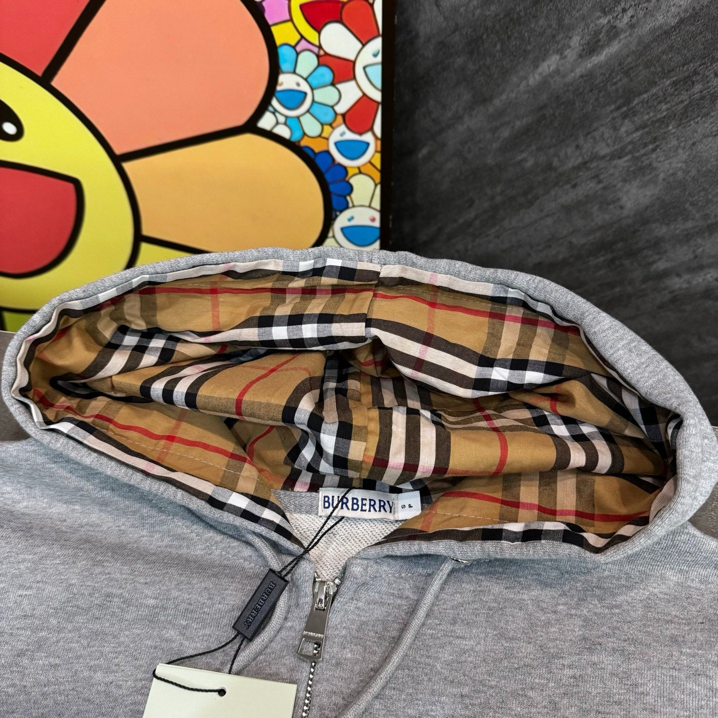 Gray hoodie close-up: plaid hood lining and Burberry size label