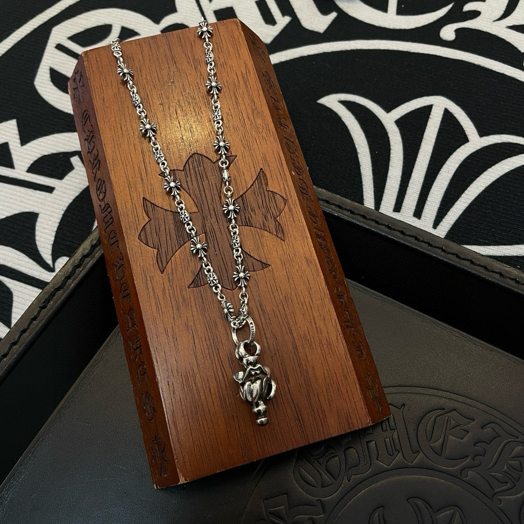 Chrome accessories silver-tone necklace with central pendant on wooden display stand