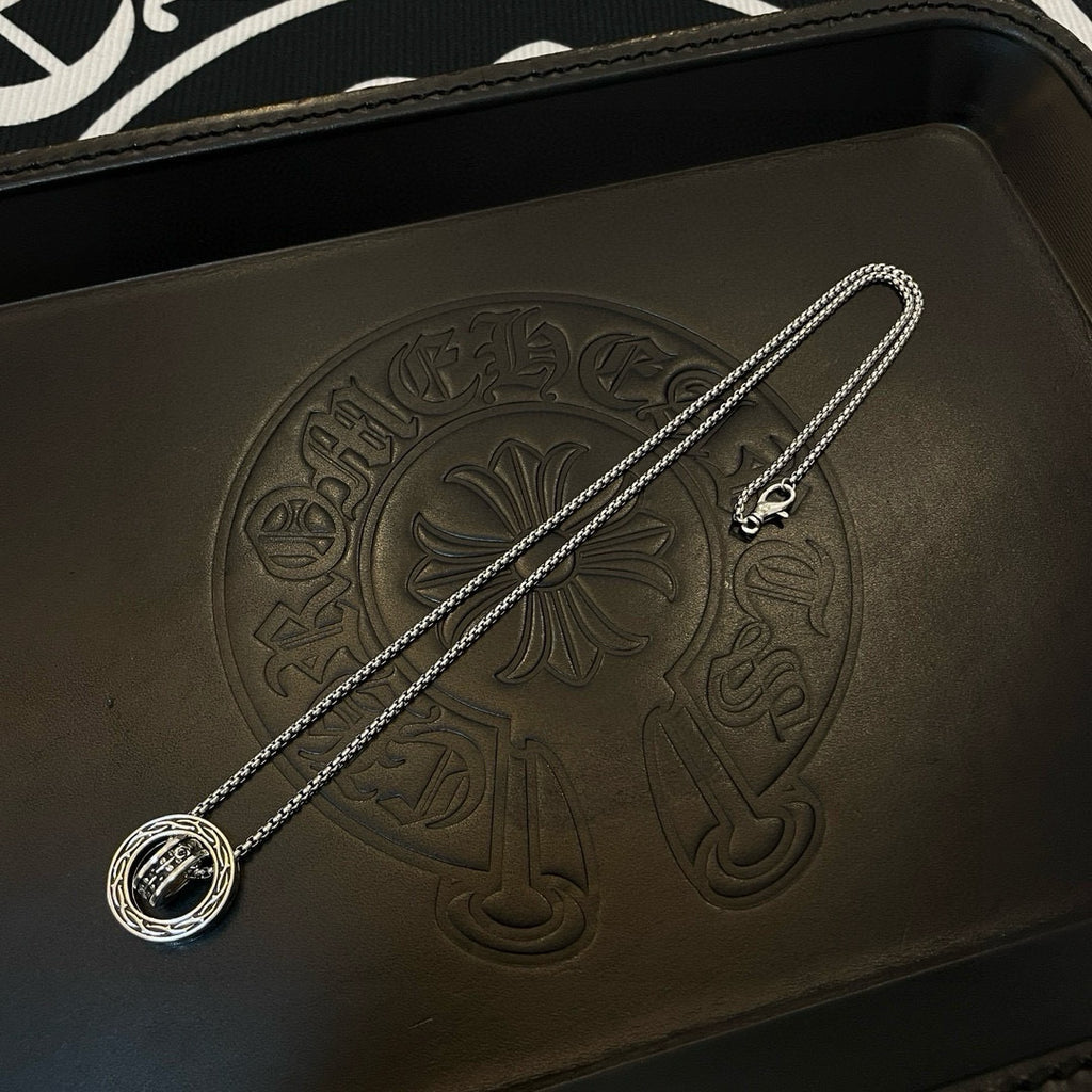 Chrome Accessories pendant necklace with round medallion on textured black leather case.