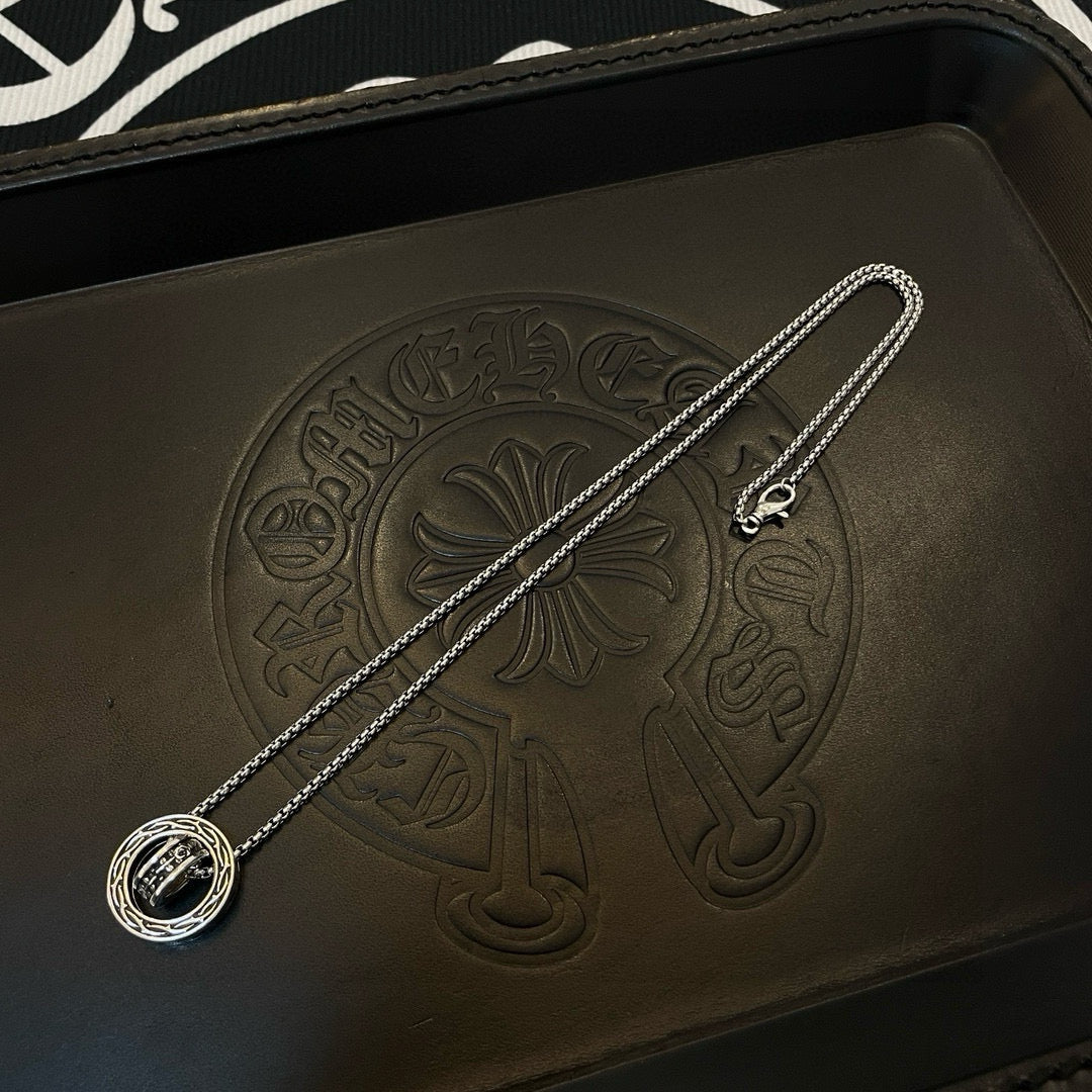 Chrome Accessories pendant necklace with round medallion on textured black leather case.