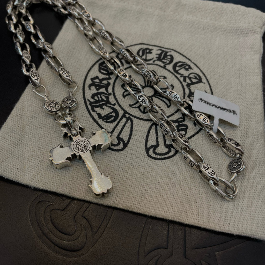 Silver cross pendant necklace on pouch with layered chain and charm details