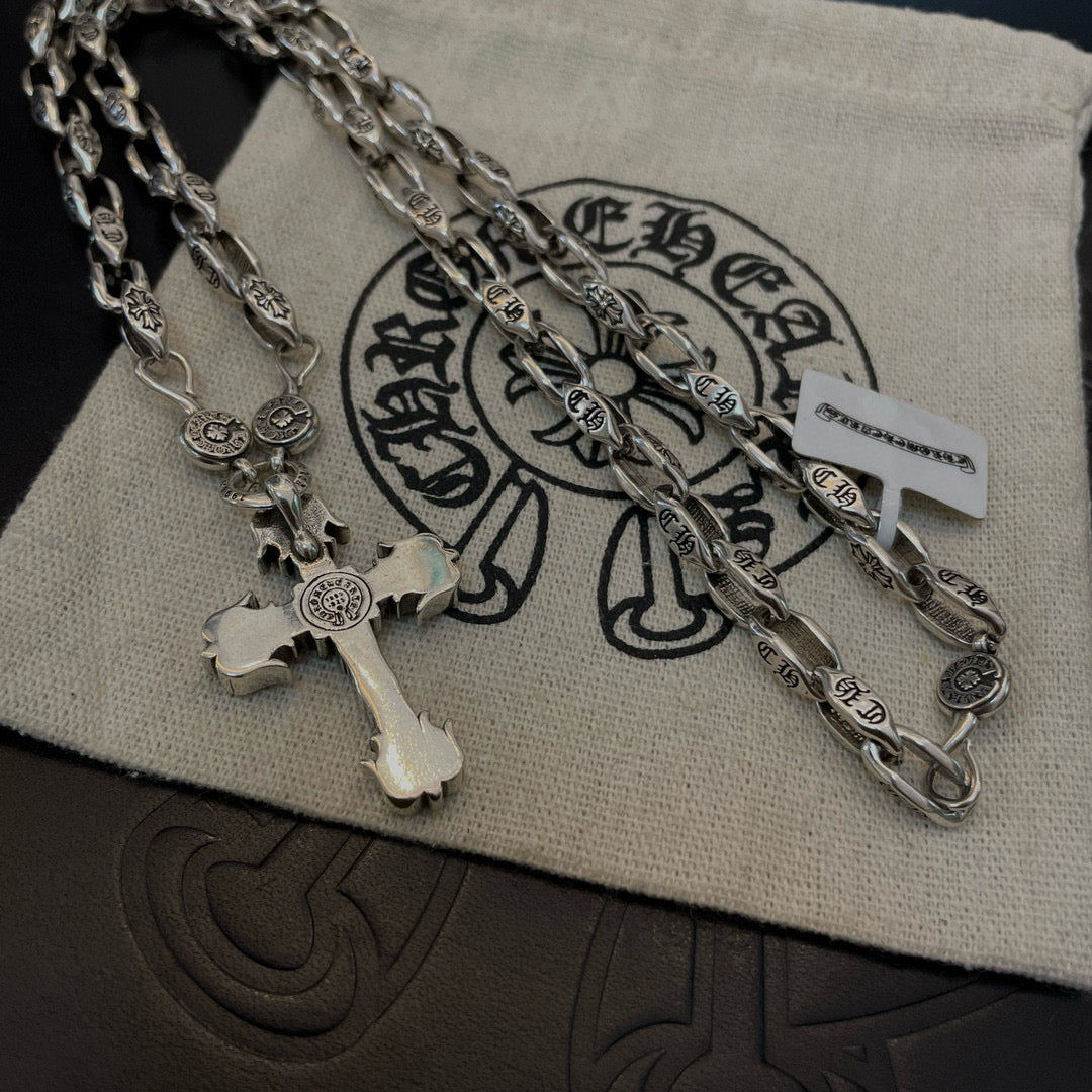 Silver cross pendant necklace on pouch with layered chain and charm details