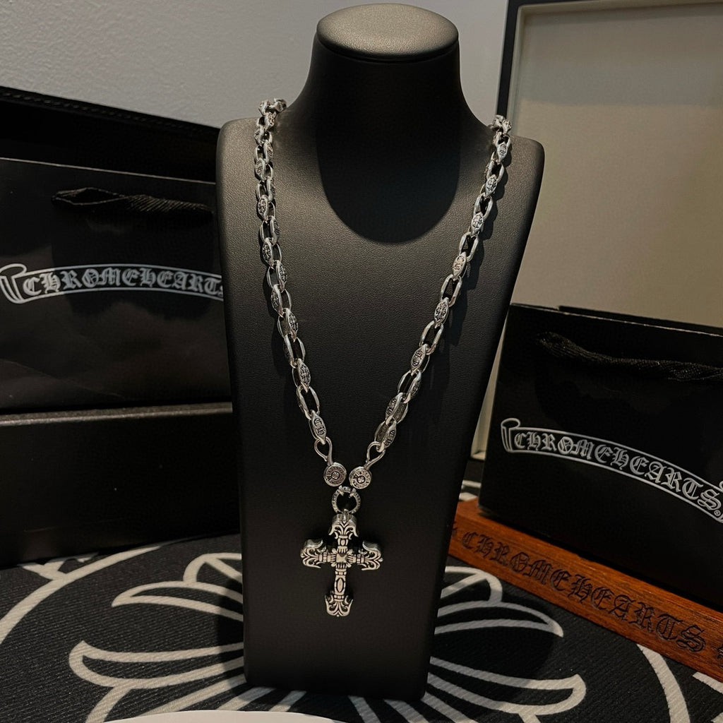 Silver chain cross pendant necklace on black display stand, front view