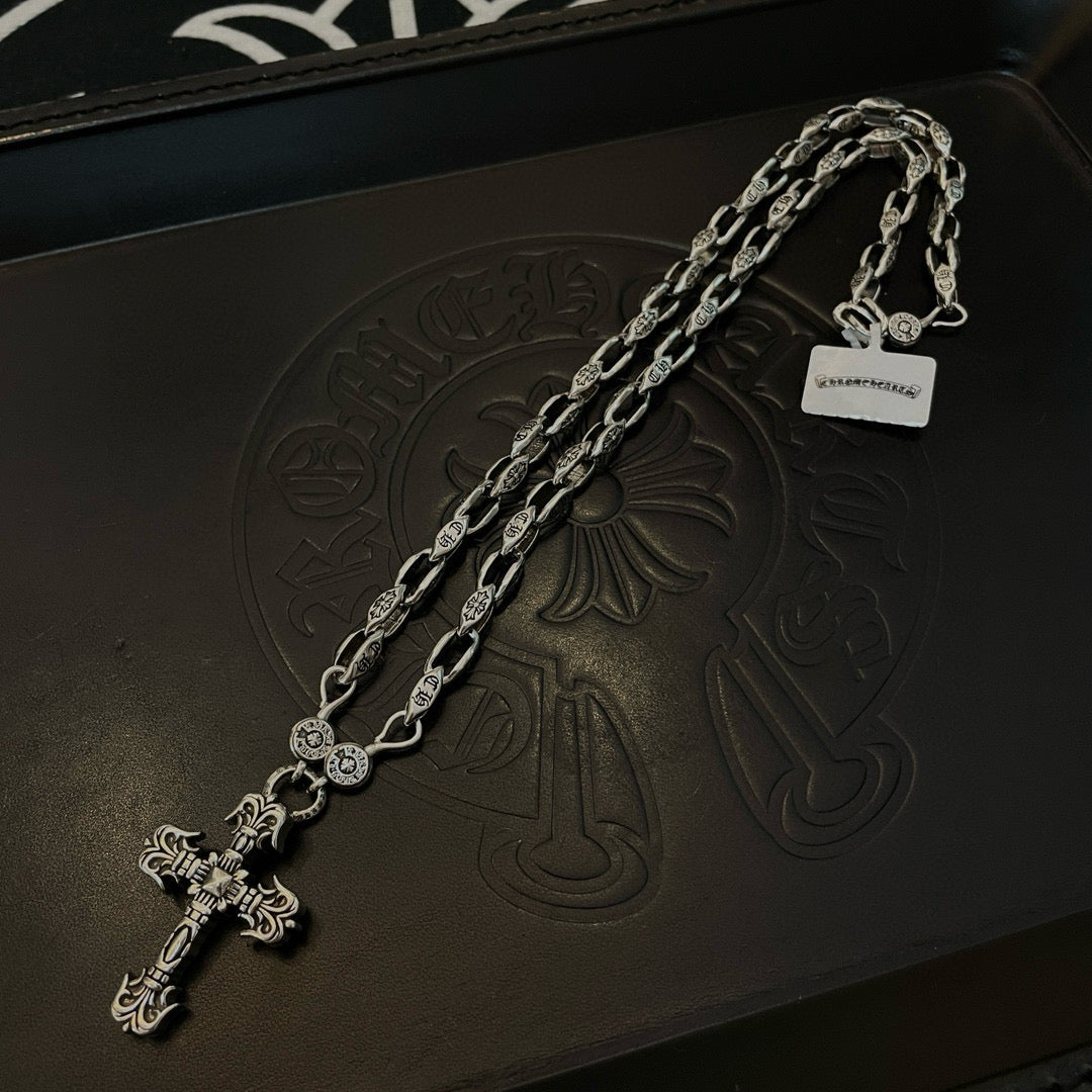 Silver chain necklace with cross pendant and engraved charm, on dark box