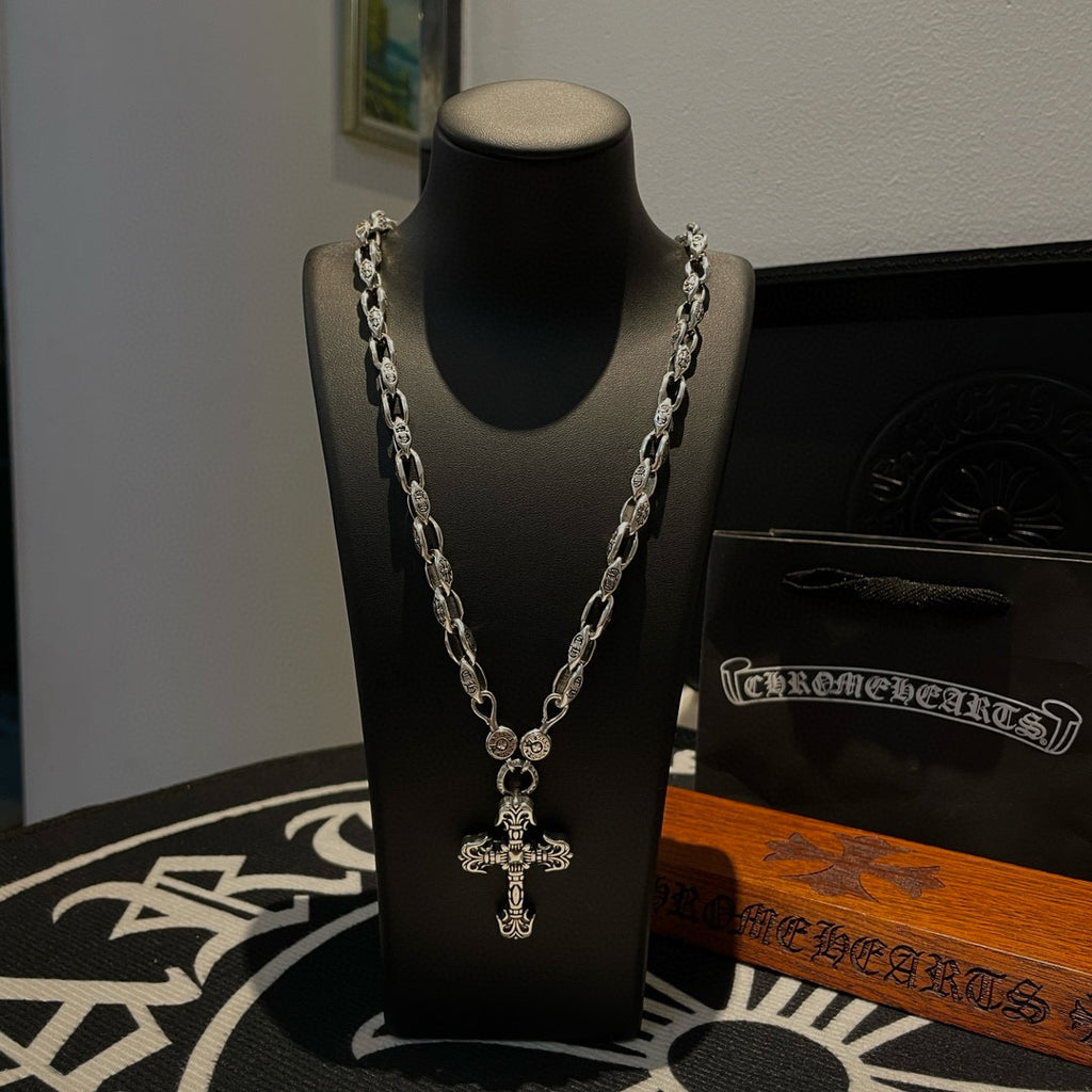 Silver chain cross pendant necklace on black display stand