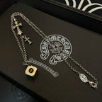 Silver cross charm necklace with round logo pendant on a black gift box